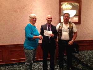 Mel Kegel and Ron Verhagen present Floberg Center President/CEO John Pingo with checks for $3000.